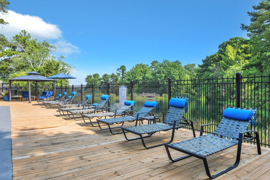 an outdoor deck with chaise lounge chairs and a black fence